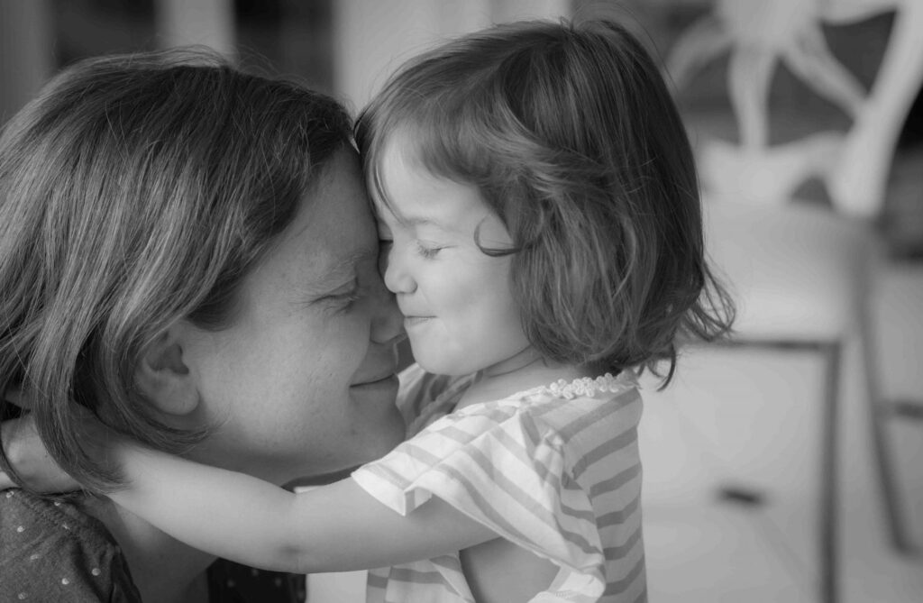 Mother and young daughter hugging with eyes closed in black & white