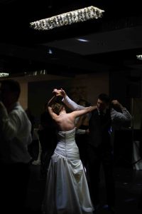 Young bride and groom dancing first dance at wedding with spotlight on bride